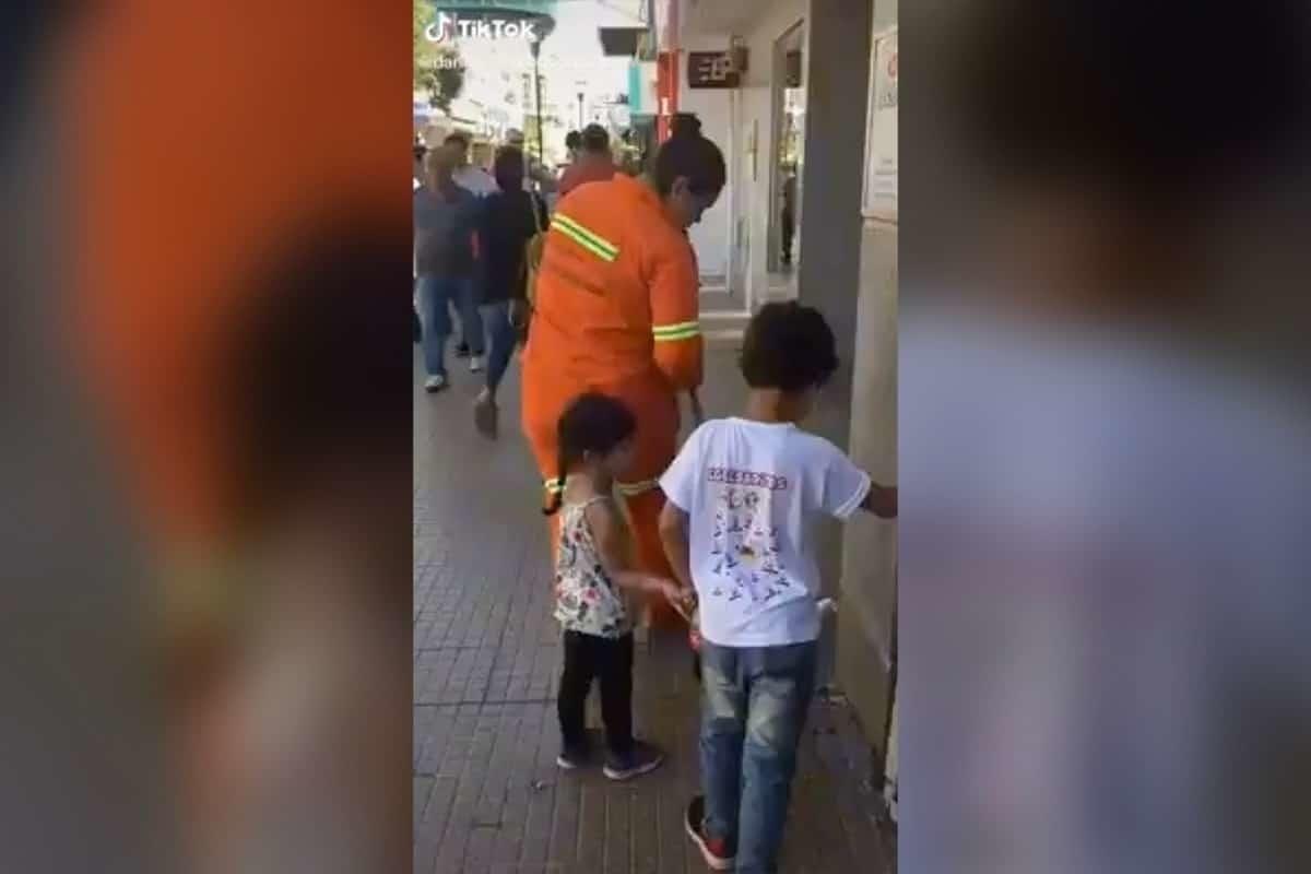 Mujer barre las calles acompañada de sus hijos