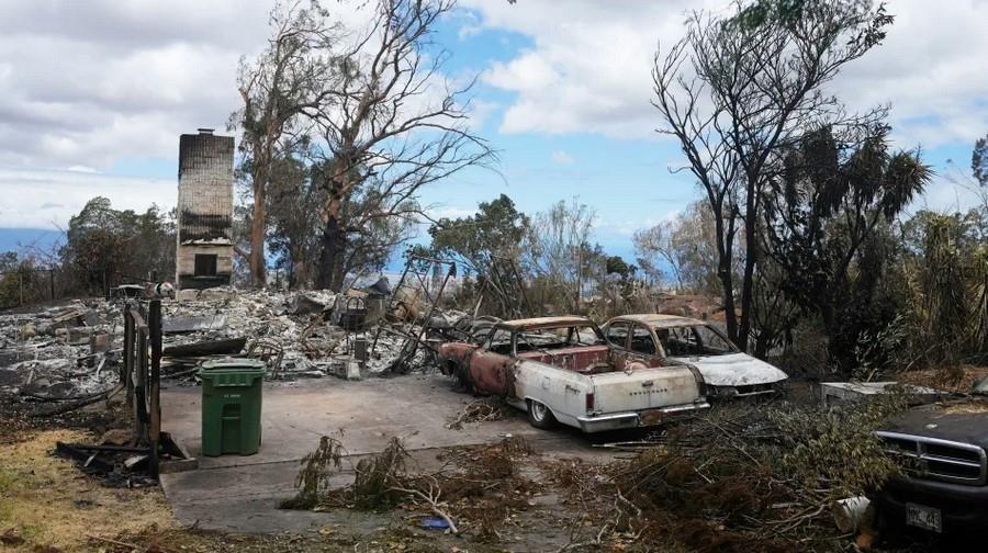 Vehículos calcinados se ven junto a una casa destruida por los incendios el lunes 14 de agosto de 2023, en Kula, Hawai.  (AP Foto/Rick Bowmer)