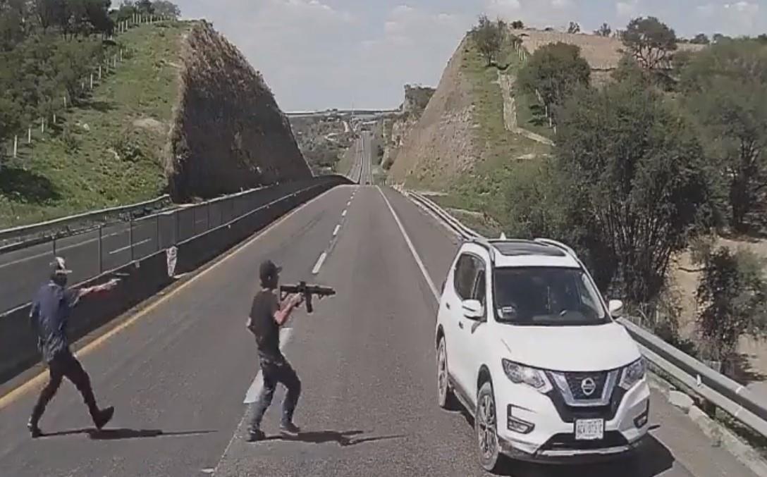 Dos hombres armados descienden de otra camioneta, portando metralletas, se acercan a la X Trail blanca y obligan a sus ocupantes a descender del vehículo. Foto: Captura de pantalla