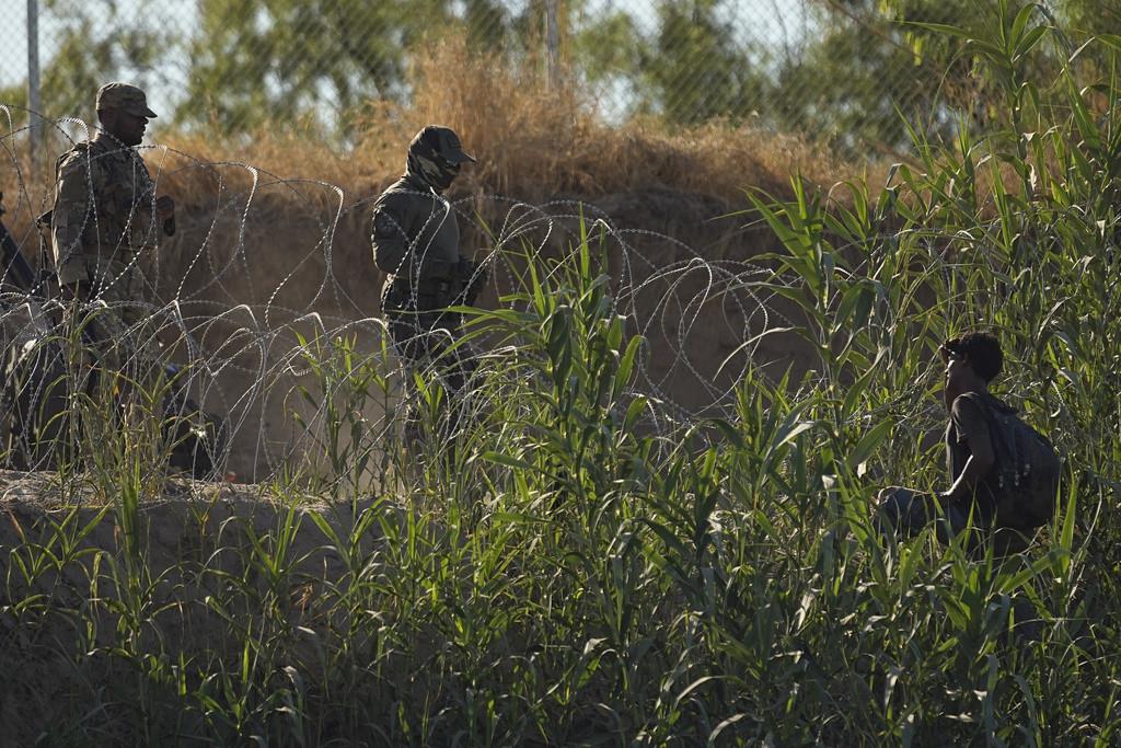 Elementos de las fuerzas de seguridad de Texas hablan con un migrante que cruzó el río Bravo (Grande) desde México, el martes 1 de agosto de 2023, en Eagle Pass, Texas. (AP Foto/Eric Gay)