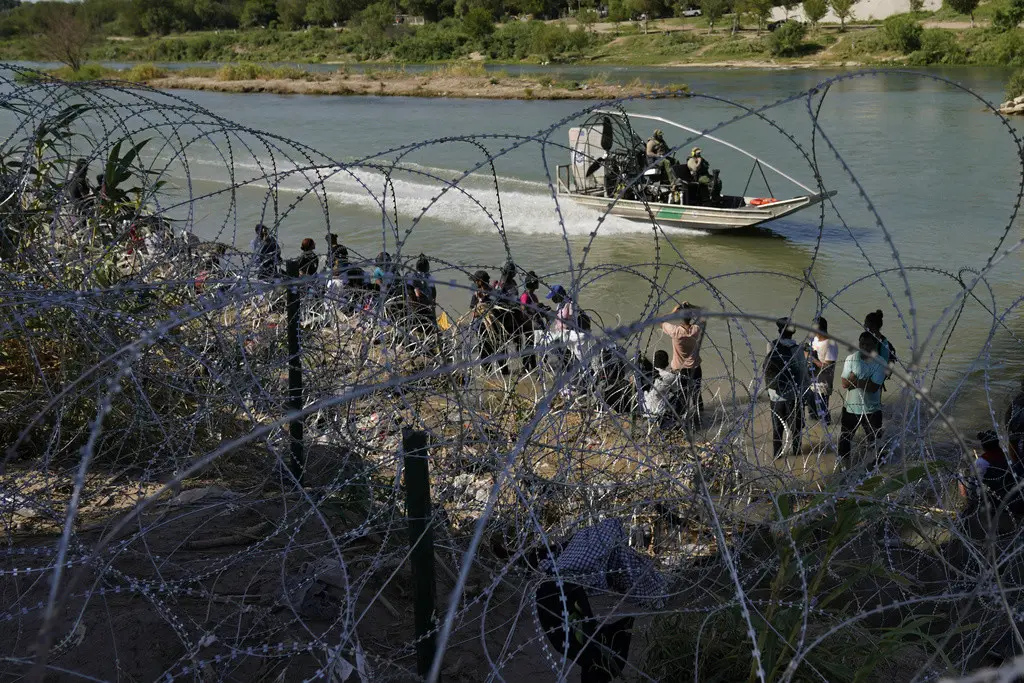 Migrantes que cruzaron a Estados Unidos desde México se encuentran con alambre de púas en la orilla del río Grande, el 21 de septiembre de 2023, en Eagle Pass, Texas. (Foto AP/Eric Gay, Archivo)