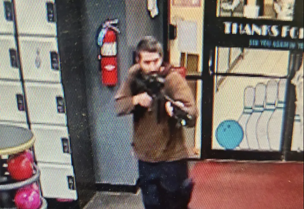 En esta imagen difundida por el Departamento de Policía del condado Androscoggin se ve a un hombre armado no identificado que apunta su fusil mientras ingresa al local Sparetime Recreation, el miércoles 25 de octubre de 2023, en Lewiston, Maine. (Departame