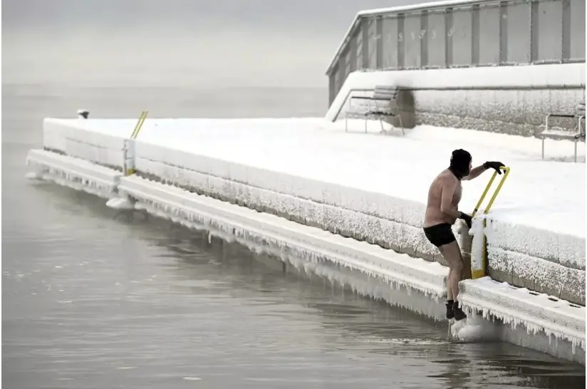 Un hombre sale del mar helado hasta el muelle, en el sur de Helsinki, Finlandia, el martes 2 de enero de 2024. Cuando las temperaturas cayeron a más de -40 grados. (Vesa Moilanen / Associated Press)