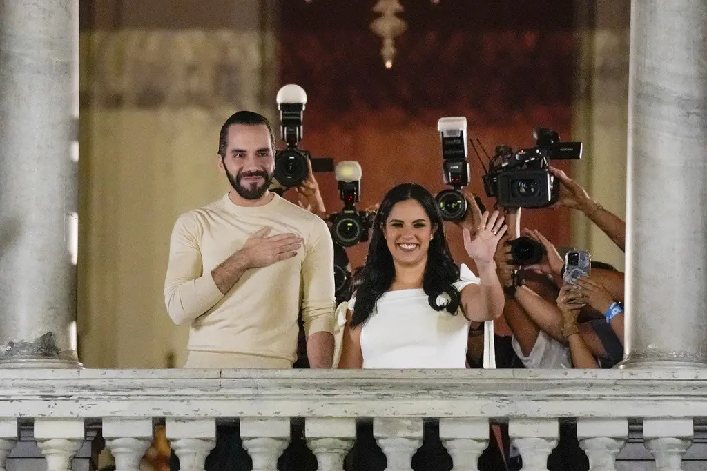 El presidente salvadoreño Nayib Bukele, izquierda, acompañado por su esposa Gabriela Rodríguez, saluda a sus seguidores desde el balcón del palacio presidencial tras el cierre de las urnas para las elecciones generales el domingo 4 de febrero de 2024, en S