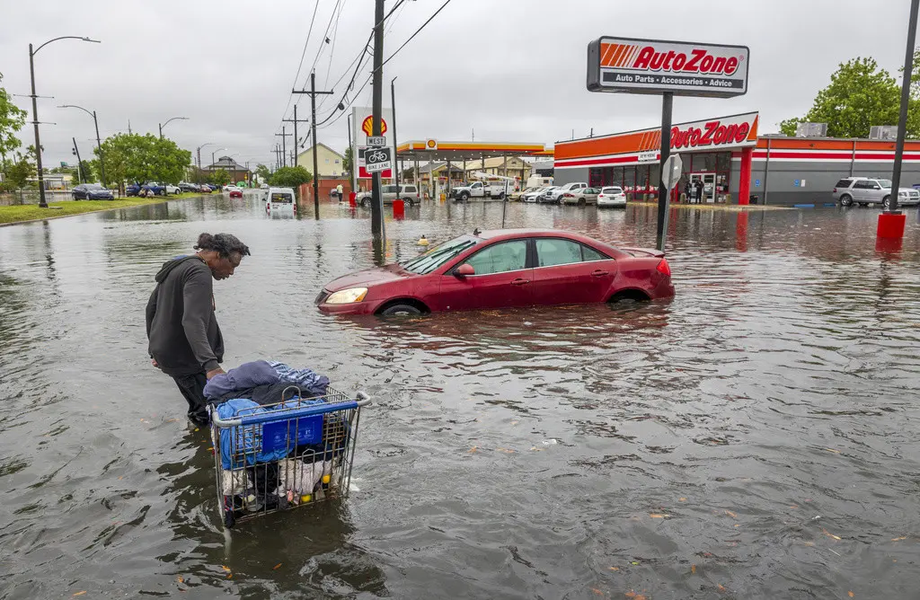 Una persona carga sus pertenencias en medio de una inundación en Broad Street el miércoles 10 de abril de 2024, en Nueva Orleans. (Chris Granger/The Times-Picayune/The New Orleans Advocate vía AP)