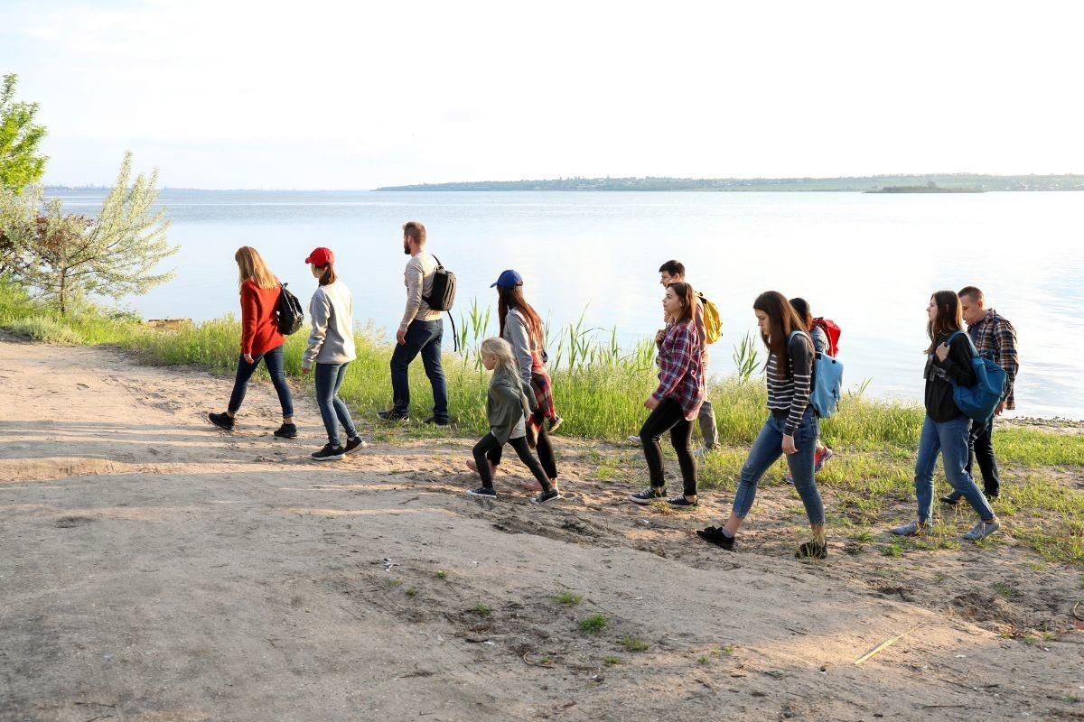 Una docena de migrantes caminando cerca de un río. Foto: Canva