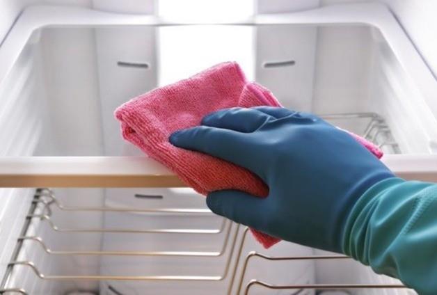 Una persona limpiando el refrigerador para darle mantenimiento adecuado. Foto: iStock.