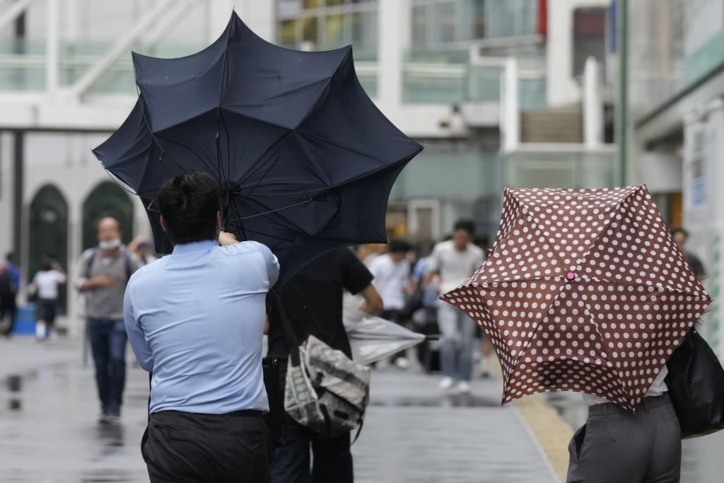 Un hombre pasa problemas para mantener el paraguas abierto a causa de los fuertes vientos del tifón Ampil, en una calle de Tokio, Japón, el 16 de agosto de 2024. (AP Foto/Hiro Komae)