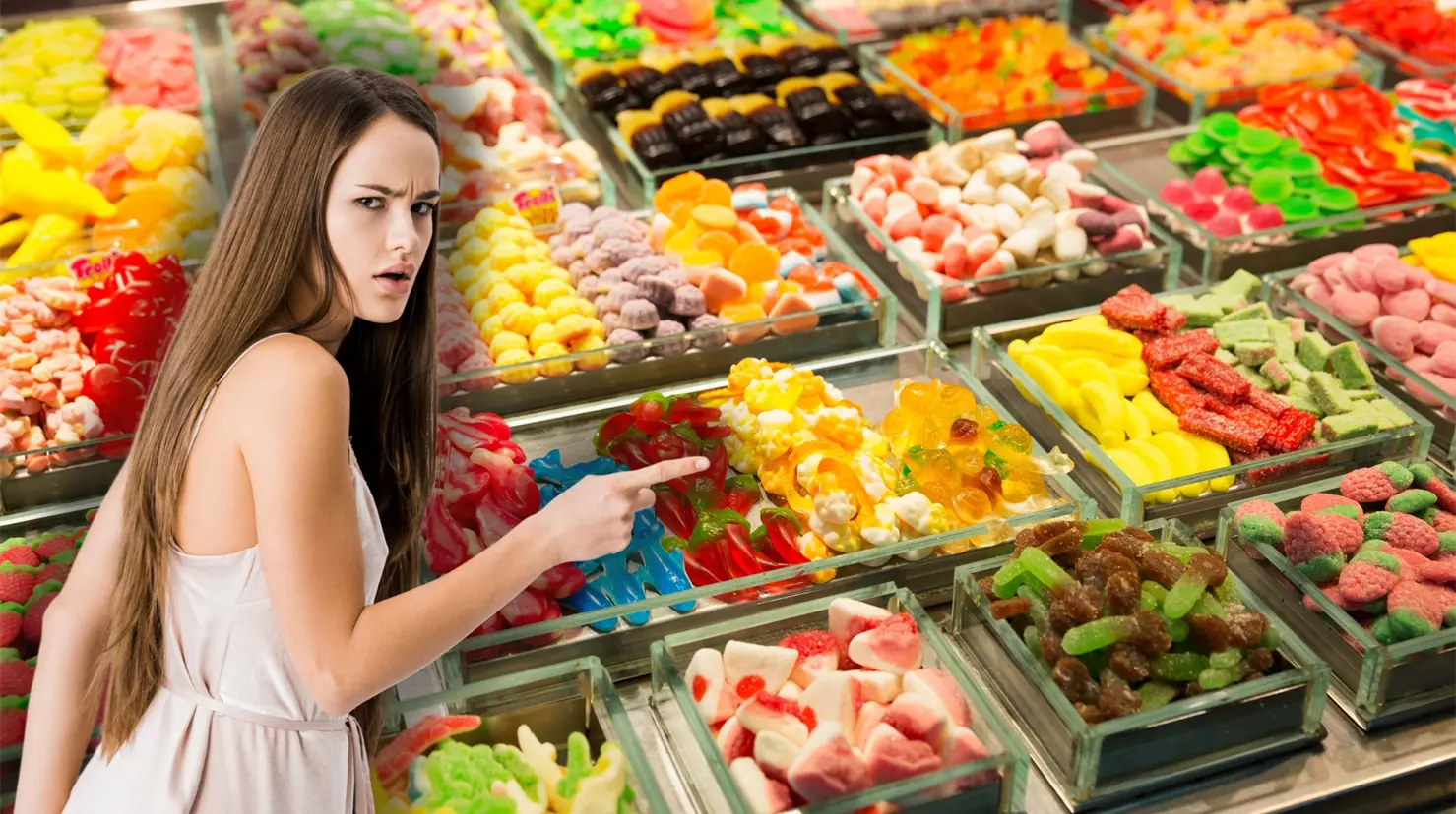 Mujer apuntando y de fondo una mesa de dulces Foto: Canva